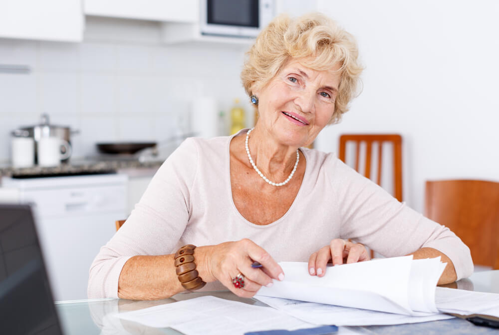 Older woman with paperwork on the kitchen table